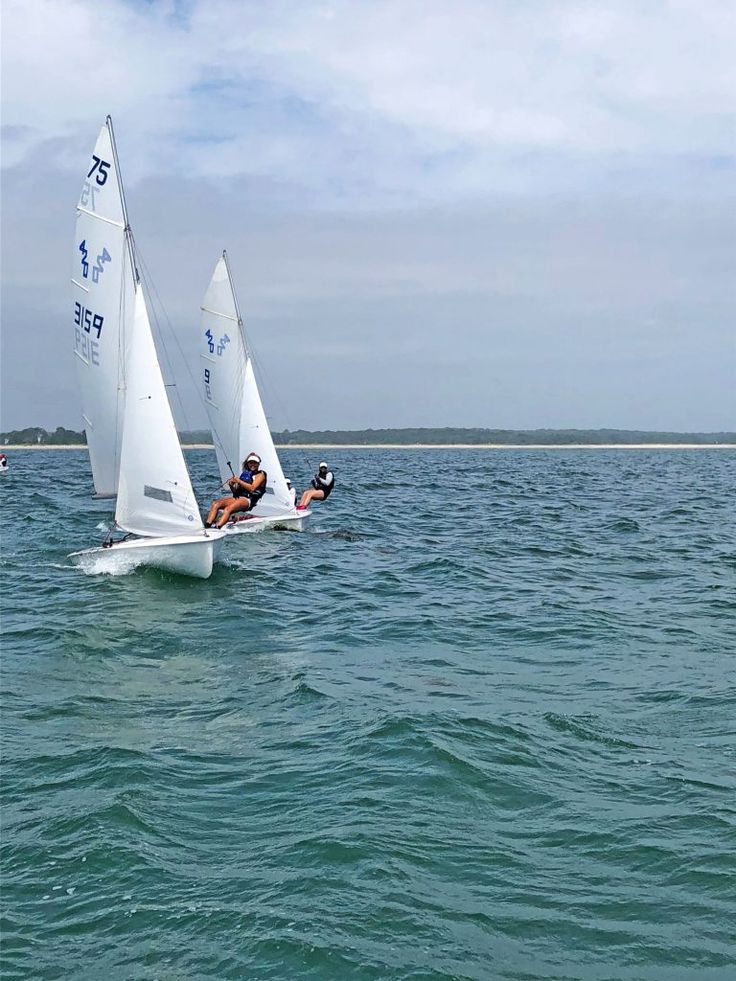 two people on sailboats in the water