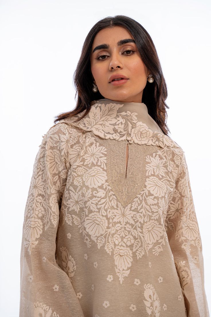 A short beige khaddi corduroy shirt with aari and tilla embroidery is paired with a matching worked organza dupatta. Playful tassel detailing complements the shirt and an embroidered rawsilk shalwar completes the look. Model Height is 5'2 and Shirt Length is 35' Beige Salwar Suit, Eid Elegant Tussar Silk Blouse, Traditional Tissue Silk Kurta With Naqshi, Traditional Naqshi Kurta In Tissue Silk, Traditional Naqshi Tissue Silk Kurta, Elegant Tussar Silk Blouse With Dupatta, Elegant Tussar Silk Kurta With Chikankari Embroidery, Tussar Silk Long Sleeve Traditional Wear With Chikankari Embroidery, Traditional Lawn Suit In Tissue Silk With Naqshi