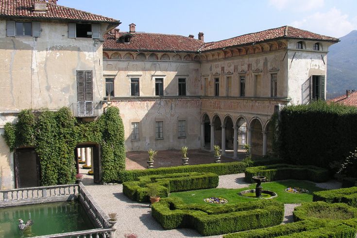 an outdoor courtyard with hedges and water feature