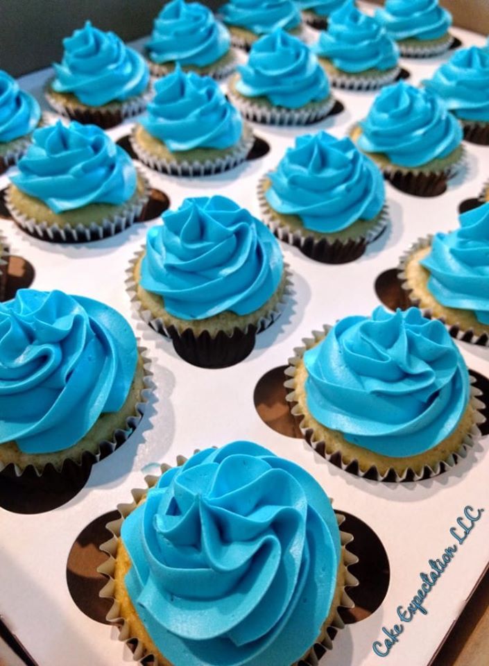 blue frosted cupcakes sitting on top of a white box