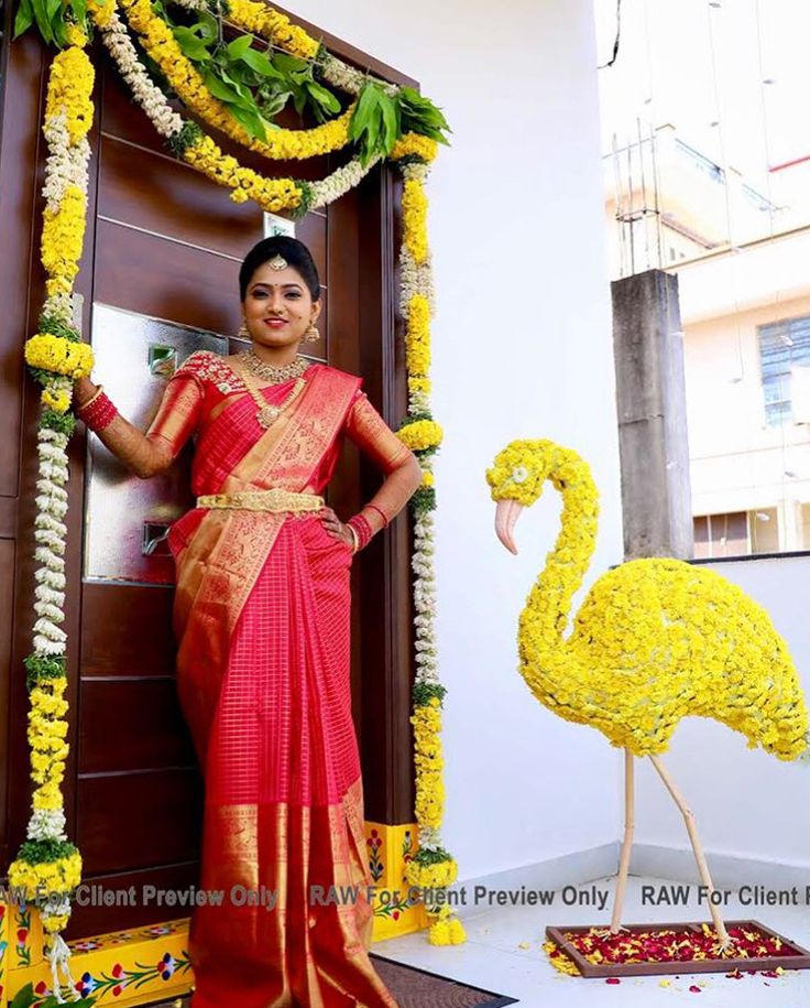 a woman in a red and gold sari standing next to a flamingo statue