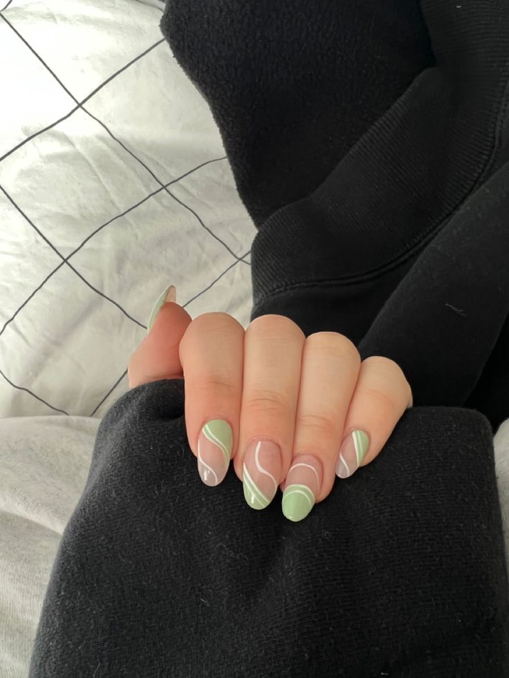 a woman with green and white nail polish on her nails