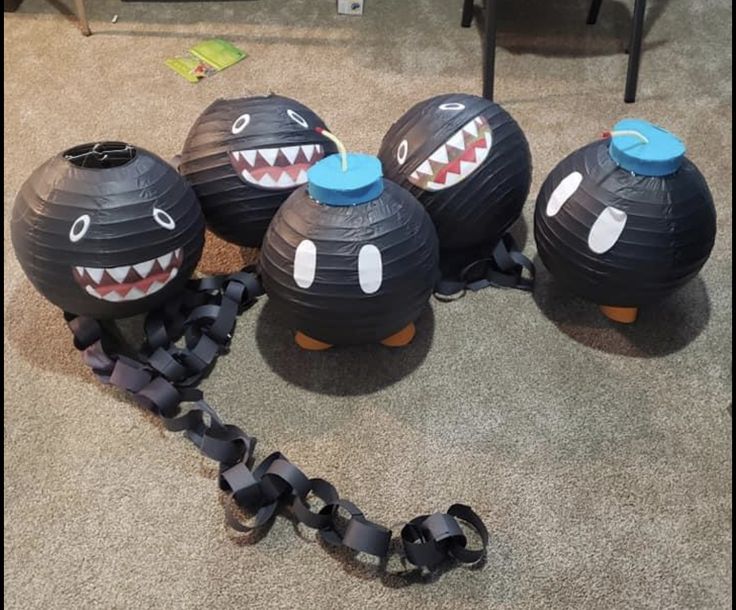 four black paper balls with mouths and teeth on them sitting on the floor next to a chair