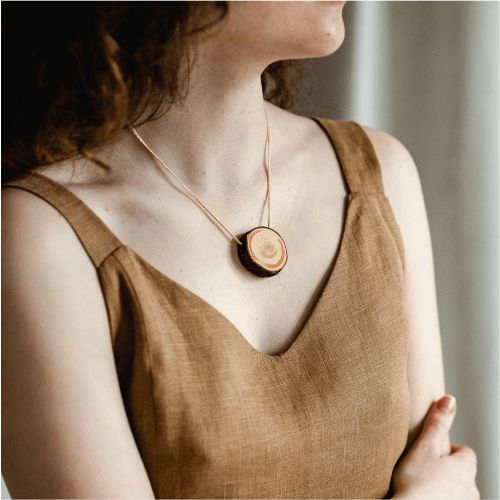 a woman wearing a necklace with a wooden disc on it