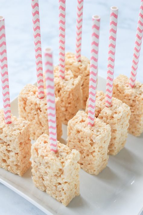 rice krispy treats with pink and white striped paper straws on a square plate