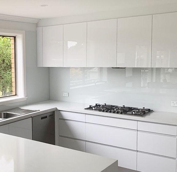 a kitchen with white cabinets and counter tops next to a window that has trees outside