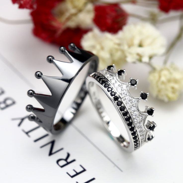 two wedding rings with black and white diamonds on them, one is wearing a crown