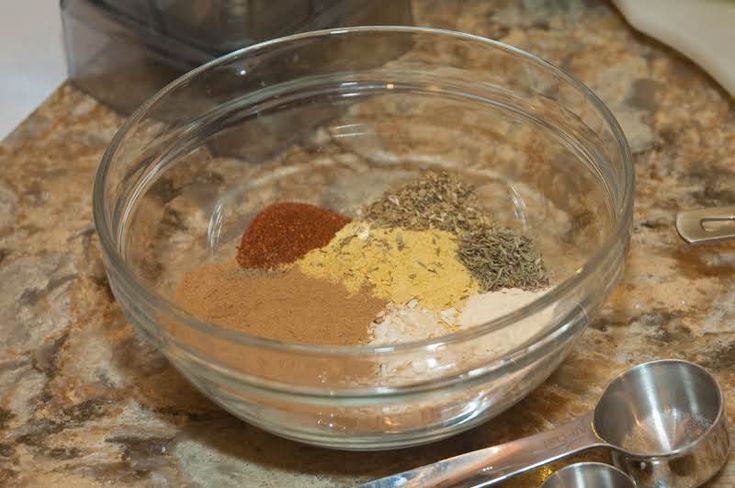 a bowl filled with spices on top of a counter next to two measuring spoons