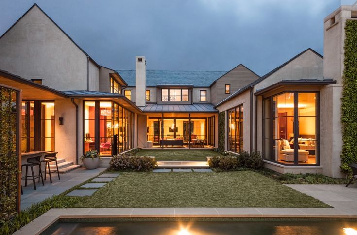 an exterior view of a house with lights on the front lawn and pool in the back yard