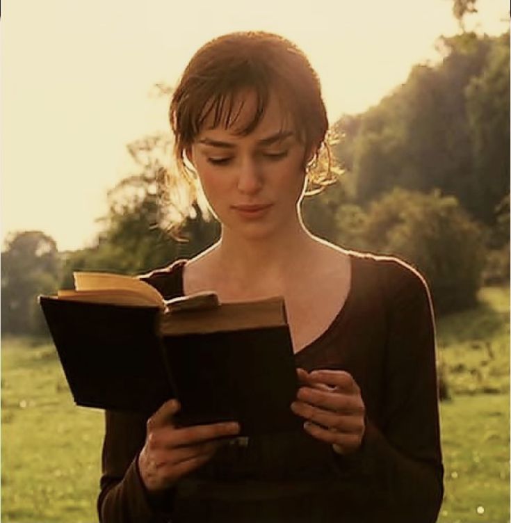 a woman is reading a book in the grass