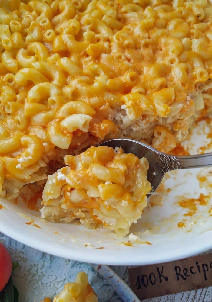 macaroni and cheese casserole in a white dish with a spoon resting on it