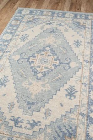 a blue and white rug with an ornate design on the bottom, in a wood floor