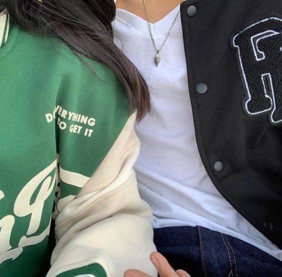 two people sitting next to each other wearing green and white jackets with the letter f on them