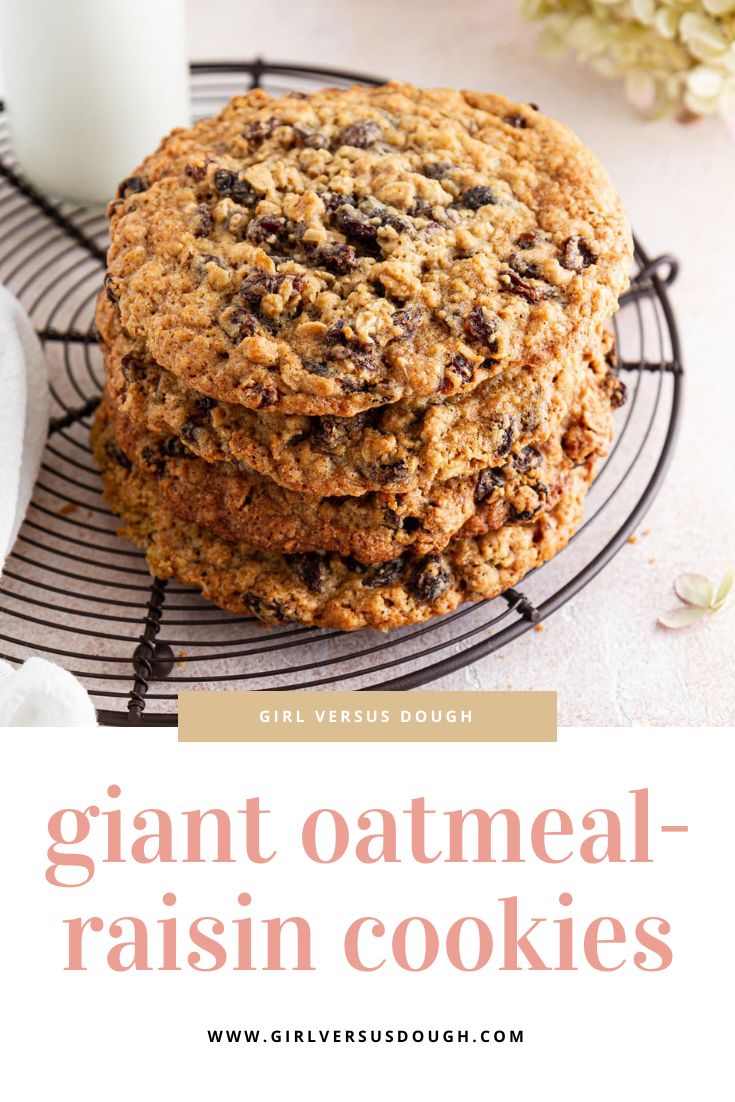 two giant oatmeal raisin cookies on a cooling rack next to a glass of milk