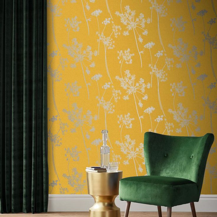 a green chair sitting in front of a yellow wall with white flowers on the wall