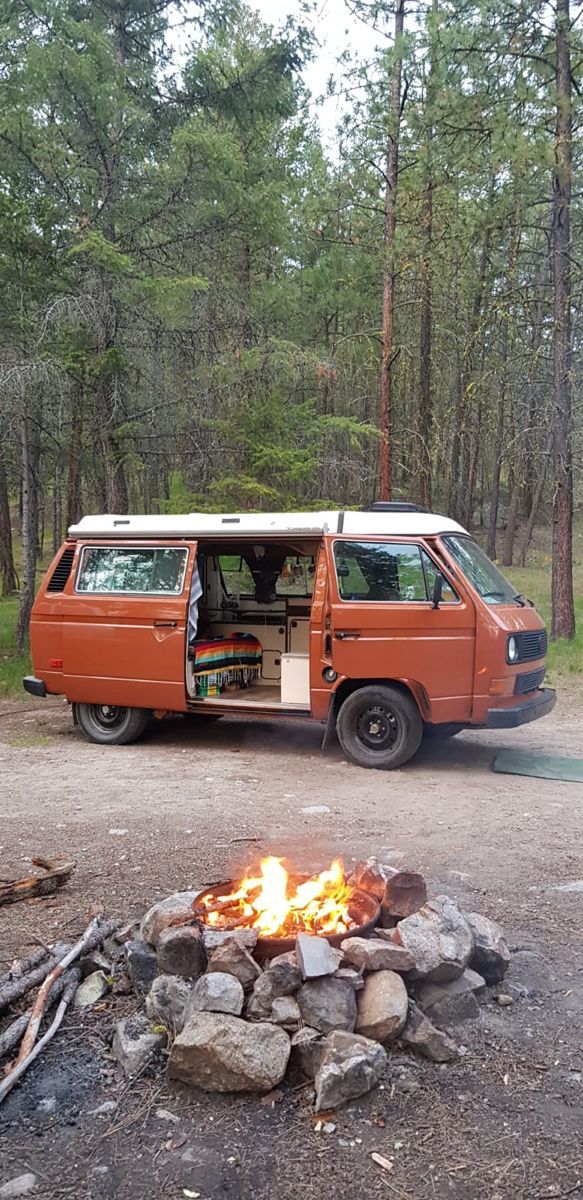 an orange van is parked next to a campfire