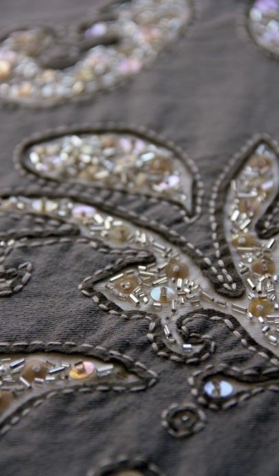 an embroidered cloth with beads and sequins is shown in close up on the surface