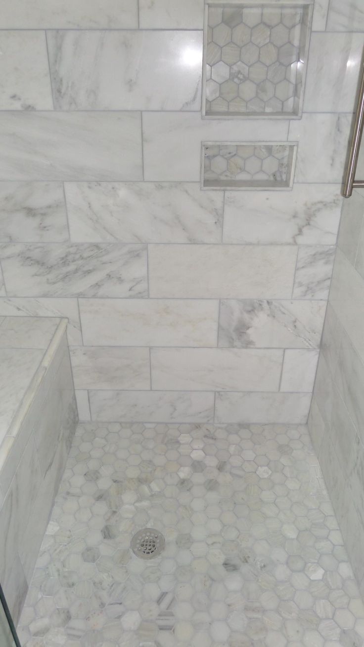 a bathroom with white marble tile and hexagonal pattern on the shower wall, along with a tiled floor