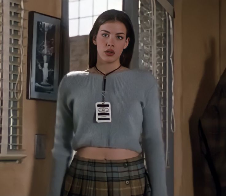 a woman in a grey sweater and plaid skirt