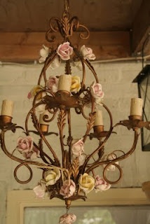 a chandelier hanging from the ceiling with flowers on it