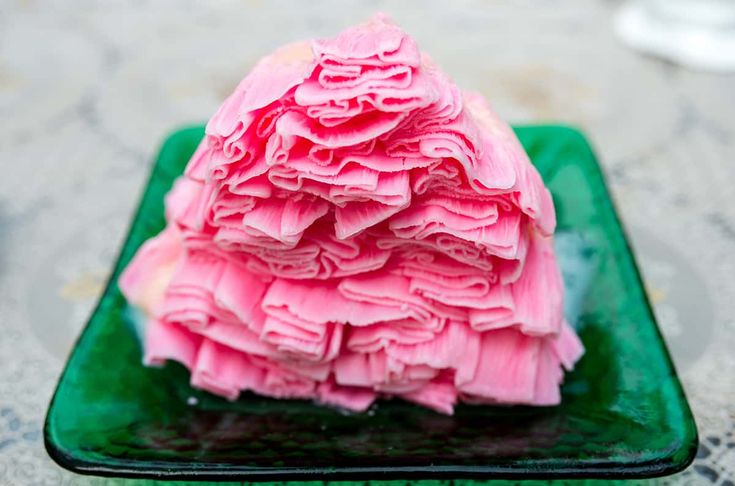 a green plate topped with pink frosting on top of a table