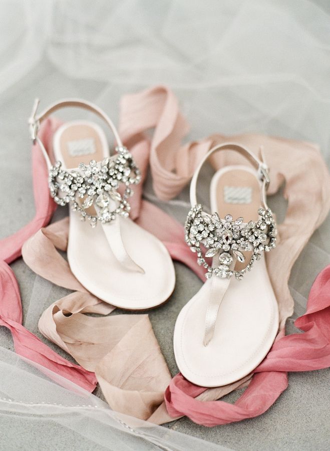 a pair of white sandals with pink satin ribbons and jeweled buckles on them