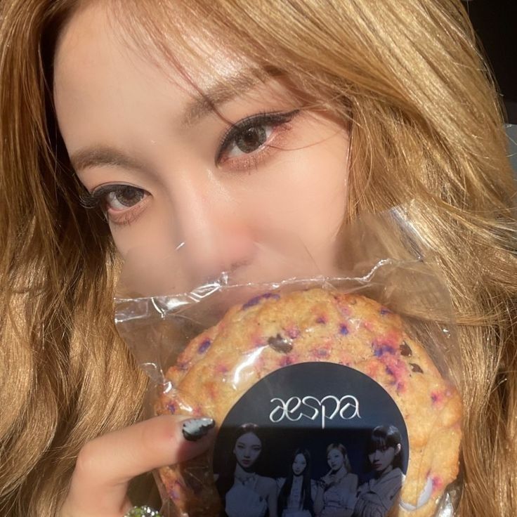 a woman holding up a doughnut with the word kiss on it's side