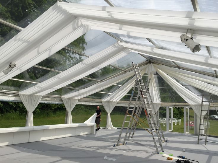 a man standing on a ladder in front of a white tent