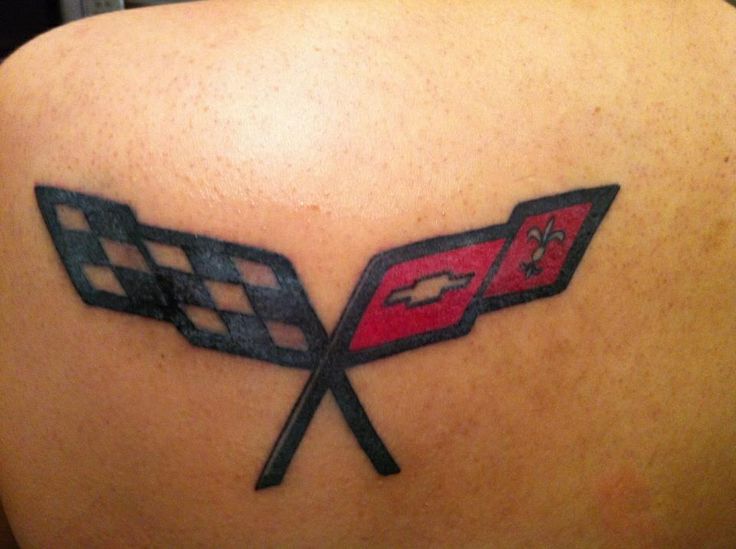 the back of a woman's shoulder with two crossed racing flags tattoo on it