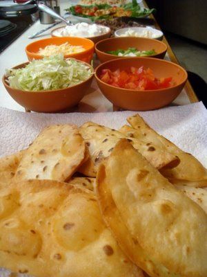 some pita breads and bowls of salad on a table with utensils