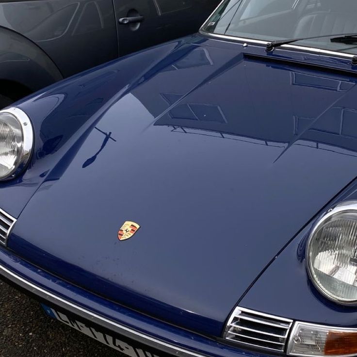 the front end of a blue sports car parked next to other cars in a parking lot