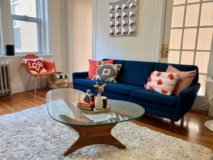 a living room filled with furniture and a glass table on top of a white rug