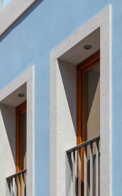 two windows on the side of a blue building