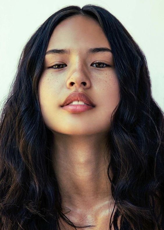 a woman with freckles on her face and chest is looking to the side