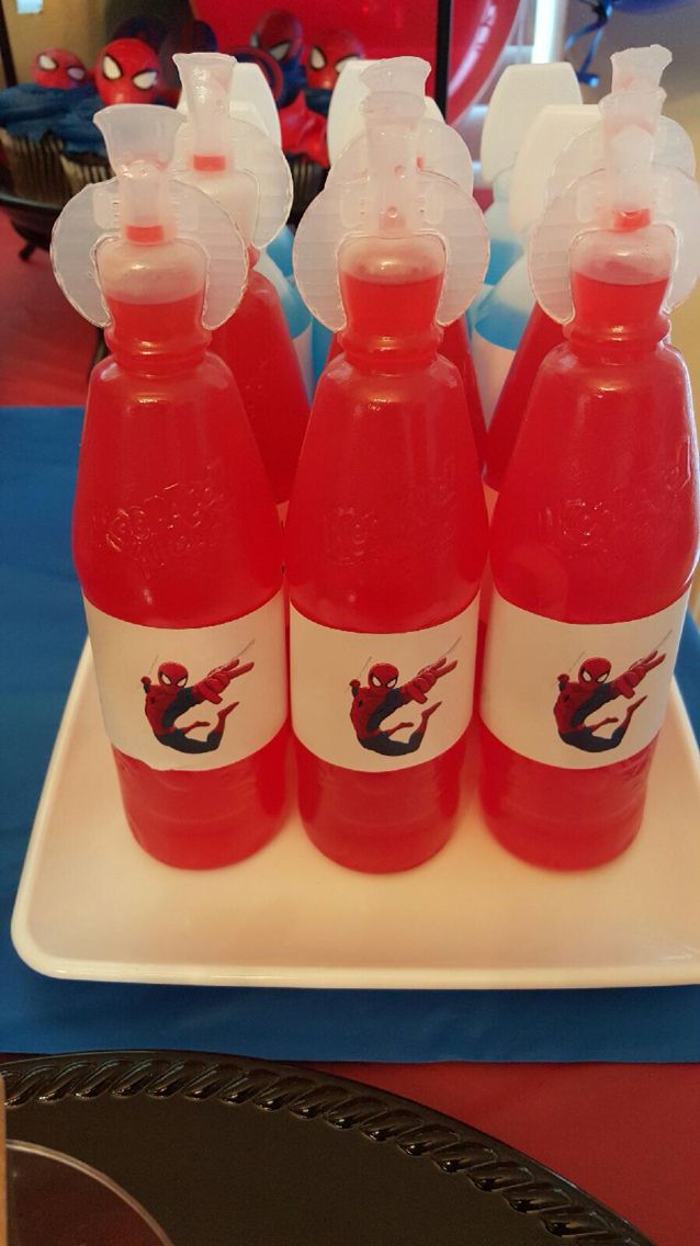 four plastic bottles with red liquid in them on a white tray and blue table cloth