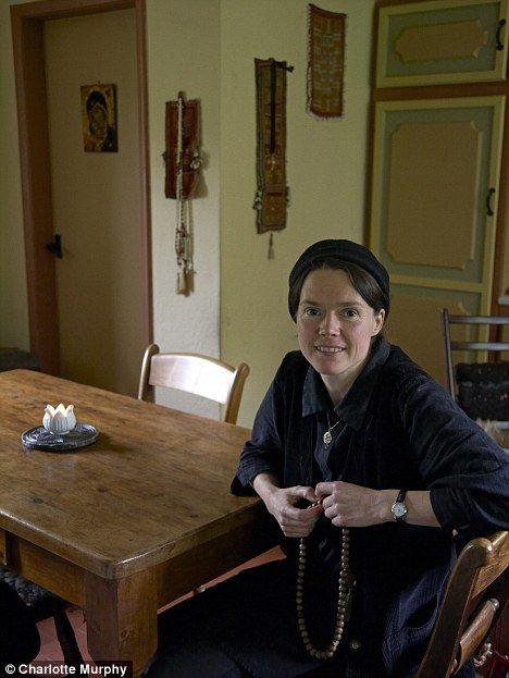 a woman sitting at a table with a rosary in her hand