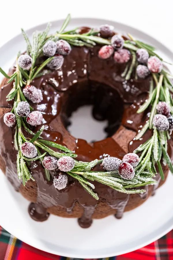 a chocolate bundt cake with frosting and sprinkles on a white plate