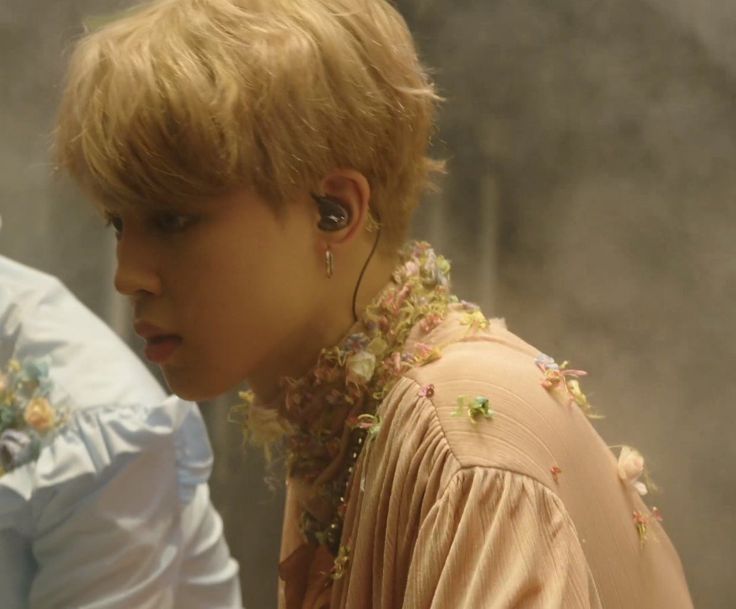 a young boy with ear buds on his ears looking at something in the distance while standing next to another person