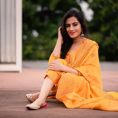 a woman sitting on the ground wearing a yellow dress