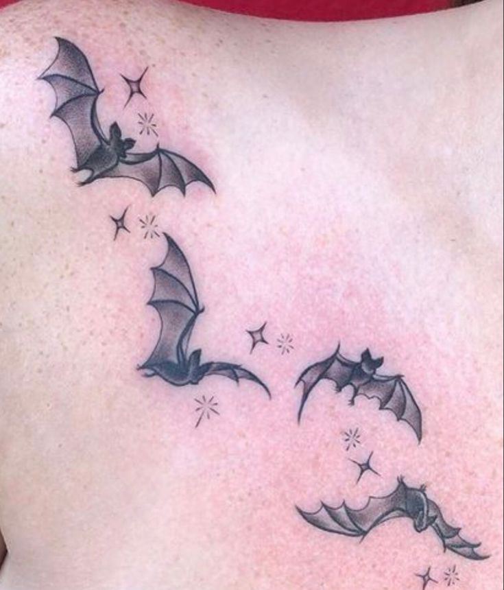 a woman's back with three bats flying through the air and stars in the sky