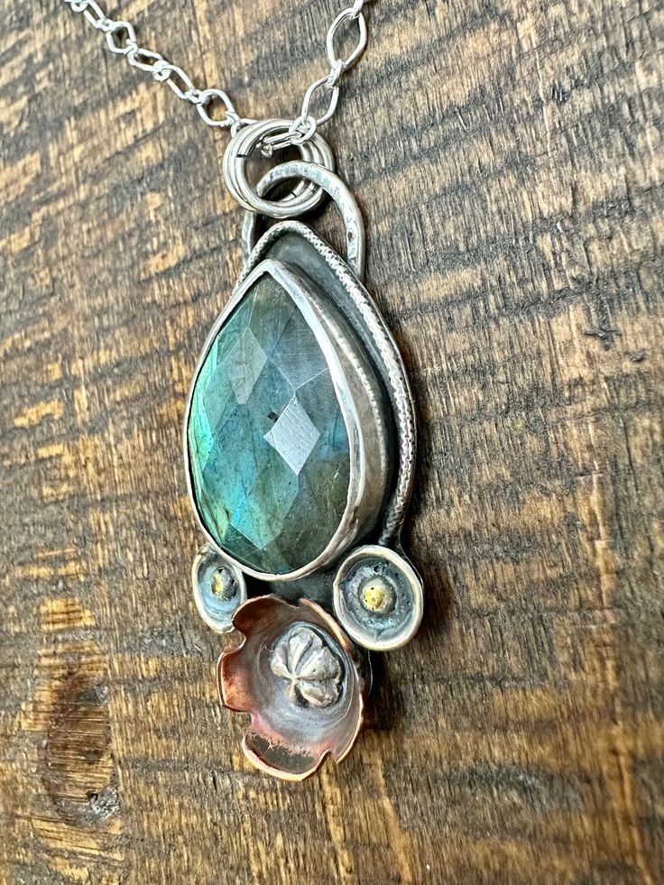 Labradorite is a beauty of a gem! It’s iridescent colors are amazing. It’s no wonder it’s know for sparking creativity! This mixed metal piece feature hand formed flowers of copper and silver with brass adornments. This little beauty is 1” wide and almost 2” total length, it comes on a 20”sterling silver necklace. Unique Hand Forged Bronze Jewelry, Silver Nature-inspired Copper Jewelry, Artisan Metal Jewelry With Patina, Unique Flower-shaped Brass Jewelry, Silver Metal Jewelry With Patina, Silver Patina Metal Jewelry, Unique Brass Flower-shaped Jewelry, Handmade Fusion Copper Jewelry, Handmade Copper Fusion Jewelry