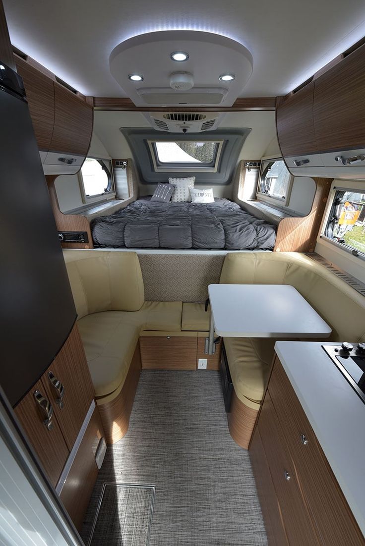 an interior view of a camper with bed and kitchen