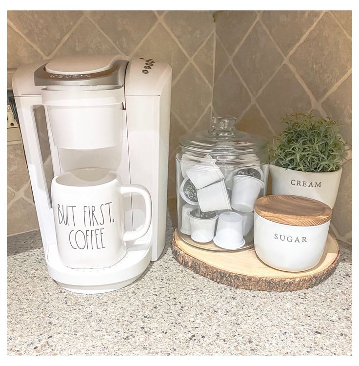 a coffee maker sitting on top of a counter next to a mug and sugar container