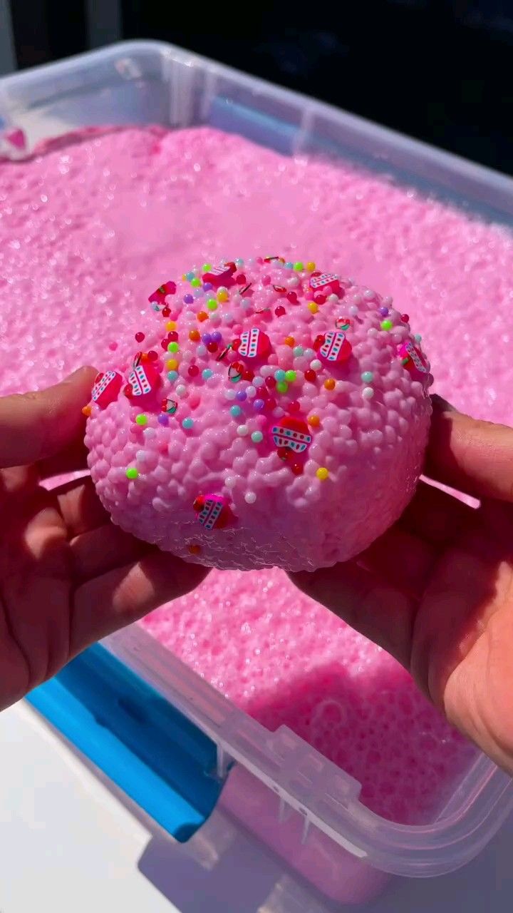 a person is holding a pink doughnut with sprinkles