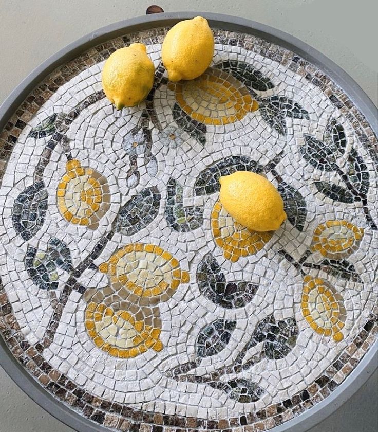 two lemons sitting on top of a mosaic table