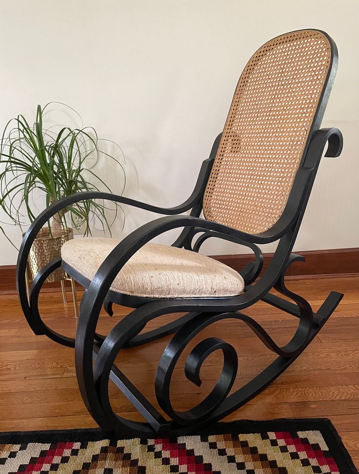 a wooden rocking chair sitting on top of a hard wood floor next to a potted plant