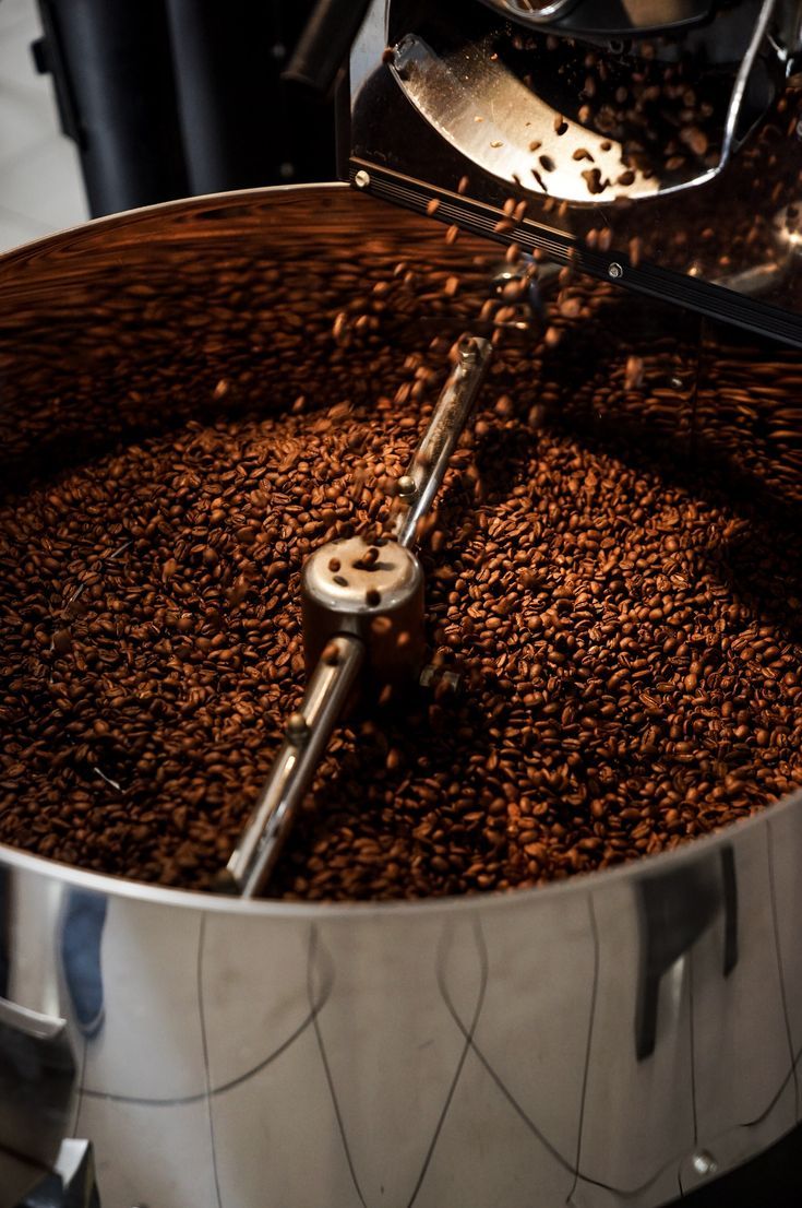 coffee being poured into a large pot filled with coffee beans and other things to make it look like they are pouring out