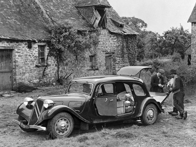 an old black and white photo of two men standing next to a car