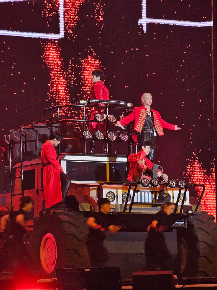 some people are performing on top of a truck in front of red and white lights