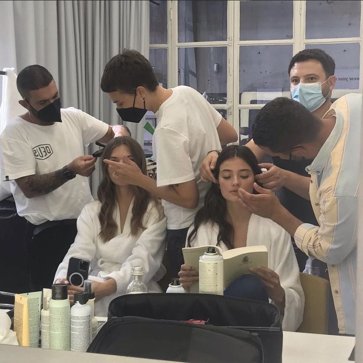 a group of people standing around each other in front of a mirror and wearing face masks